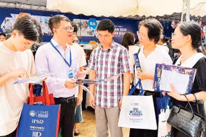 Thí sinh và phụ huynh được giải đáp thông tin tuyển sinh, chương trình đào tạo tại gian tư vấn của Đại học Kinh tế quốc dân. (Ảnh: QUỲNH NGUYỄN)