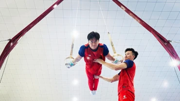 Huấn luyện viên Trương Minh Sang hỗ trợ vận động viên trong bài tập vòng treo.