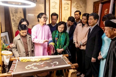 Du khách tìm hiểu nghề thêu tại đình Tú Thị, một điểm đến di sản trong tuyến đình thờ Tổ nghề.