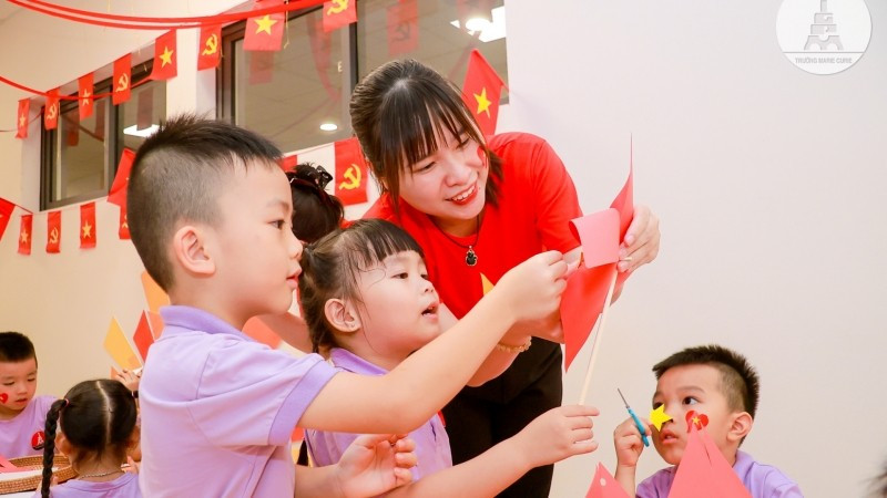 Cô và trò cùng nhau làm lá cờ đỏ sao vàng.