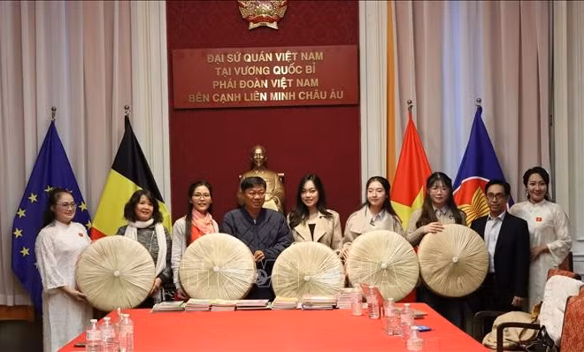 Ông Đỗ Phước Trung, Phó Giám đốc Sở Văn hóa và Thể thao Thành phố Hồ Chí Minh, trao tặng sách cho ông Huỳnh Công Mỹ, Chủ tịch Tổng hội người Việt Nam tại Vương quốc Bỉ. (Ảnh: TTXVN)