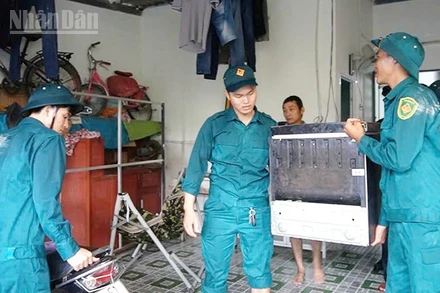 Lực lượng dân phòng hỗ trợ người dân vùng nguy cơ ngập lụt kê cao đồ đạc.