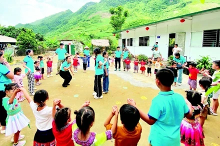 Các thành viên dự án “Đông ấm cho trẻ em vùng cao” cùng học sinh điểm trường Pa Phang 2, Trường mầm non Phìn Hồ (huyện Sìn Hồ, Lai Châu) bên hai lớp học mới khánh thành dịp Quốc tế Thiếu nhi. (Ảnh: PHONG CHƯƠNG)