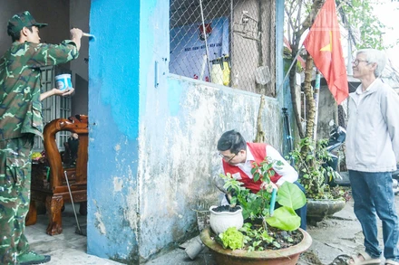 Ông Lê Văn Nam (bên phải) vui mừng khi ngôi nhà được các tình nguyện viên hỗ trợ sơn mới.