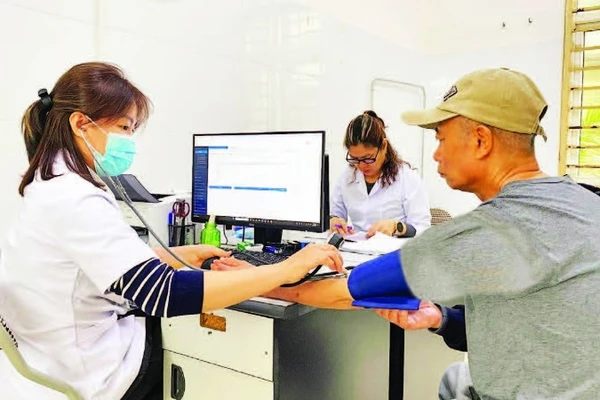 Các bác sĩ tại Trạm Y tế Long Biên khám sức khỏe cho người dân và sử dụng hệ thống dữ liệu bệnh án điện tử.