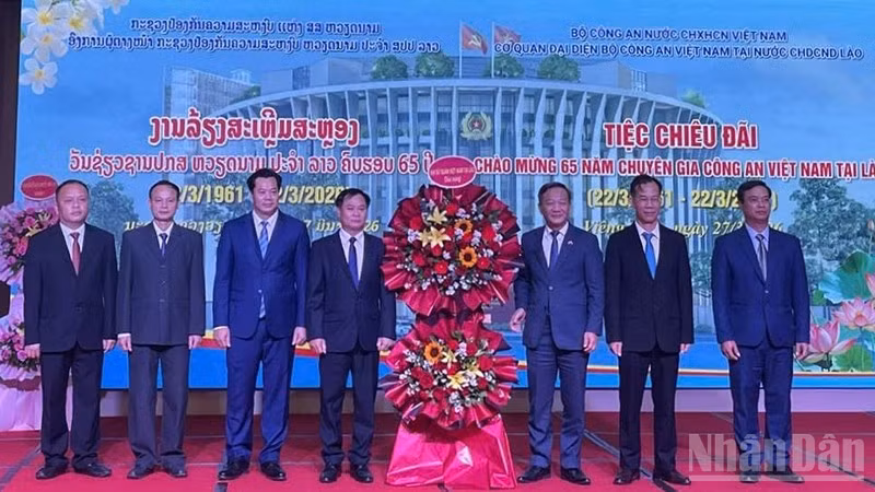 Đại sứ Nguyễn Minh Tâm (thứ 3 từ phải qua) tặng hoa chúc mừng đội ngũ Chuyên gia Công an Việt Nam tại Lào. (Ảnh: DUY TOÀN)