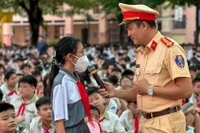 Cán bộ Phòng Cảnh sát giao thông, Thành phố Hồ Chí Minh trao đổi với một học sinh về an toàn giao thông. 