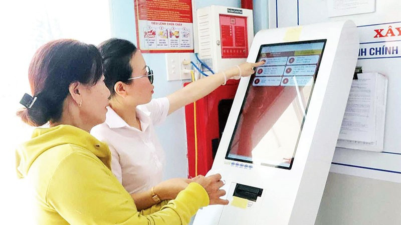 Cán bộ Trung tâm Phục vụ hành chính công xã Hòa Phú hướng dẫn người dân lấy số xếp hàng tự động.