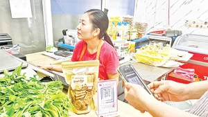 Người dân quét mã QR để thanh toán tiền khi đi chợ.