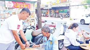 Những khách hàng đến ăn lần đầu, ông Trương Minh Đương (áo trắng) tự tay nấu mì phục vụ khách.