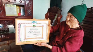 Bà Liên nâng niu tấm bằng công nhận thành tích người cao tuổi mẫu mực, nêu gương sáng vì sự nghiệp xây dựng và bảo vệ Tổ quốc.