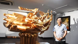 Họa sĩ, nhà điêu khắc Đinh Gia Thắng bên tác phẩm điêu khắc “Cội nguồn hạnh phúc”.