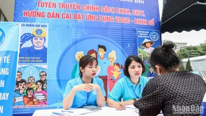 Cán bộ Bảo hiểm xã hội quận Long Biên, Hà Nội giới thiệu về chính sách bảo hiểm xã hội, bảo hiểm y tế với người dân. (Ảnh NGÂN ANH)