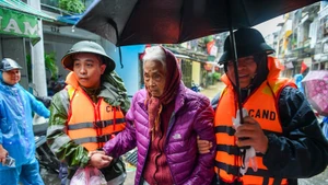 Lực lượng công an hỗ trợ người dân các phường ngoài đê sông Hồng đi sơ tán khi nước lũ dâng cao. (Ảnh: THẾ ĐẠI)