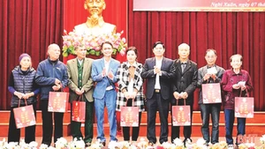 Lãnh đạo huyện Nghi Xuân và nhà tài trợ trao quà Tết tặng các gia đình nạn nhân chất độc da cam/dioxin, trẻ em mồ côi và khuyết tật. (Ảnh BHT)