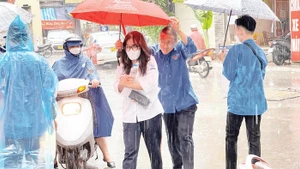 Thanh niên tình nguyện che ô, hỗ trợ thí sinh vào phòng thi.