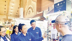Đoàn viên, thanh niên quận Hoàn Kiếm hướng dẫn các hộ kinh doanh, người mua hàng tại chợ Đồng Xuân sử dụng mã QR khi thanh toán.