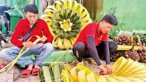 Nhóm bạn trẻ tại Tổ hợp tác cổng rạp cưới "Alo Tui" tạo hình trang trí cưới từ lá dừa.