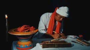 Phó Cả sư Nại Cao Liêm đang thực hiện công đoạn khắc chữ trên lá buông. (Ảnh: NGỌC XIÊM)