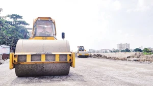 Thi công trải nhựa đường ven kênh Tham Lương, đoạn qua cầu Bến Phân đến cầu An Lộc trên địa bàn Quận 12, Thành phố Hồ Chí Minh. (Ảnh THẾ ANH)