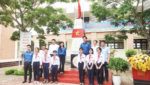 Đại biểu và các em học sinh chụp ảnh lưu niệm với Cột mốc chủ quyền biển đảo.