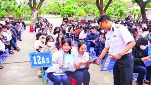 Báo cáo viên tuyên truyền, phát tờ rơi về thu hút nguồn nhân lực tại Trường THPT Hùng Vương, thành phố Quy Nhơn. (Ảnh THANH SANG)
