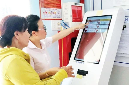 Cán bộ Trung tâm Phục vụ hành chính công xã Hòa Phú hướng dẫn người dân lấy số xếp hàng tự động.