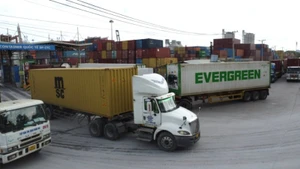 Xe container chở hàng hóa ra vào Cảng. (Ảnh: QUÝ HIỀN)