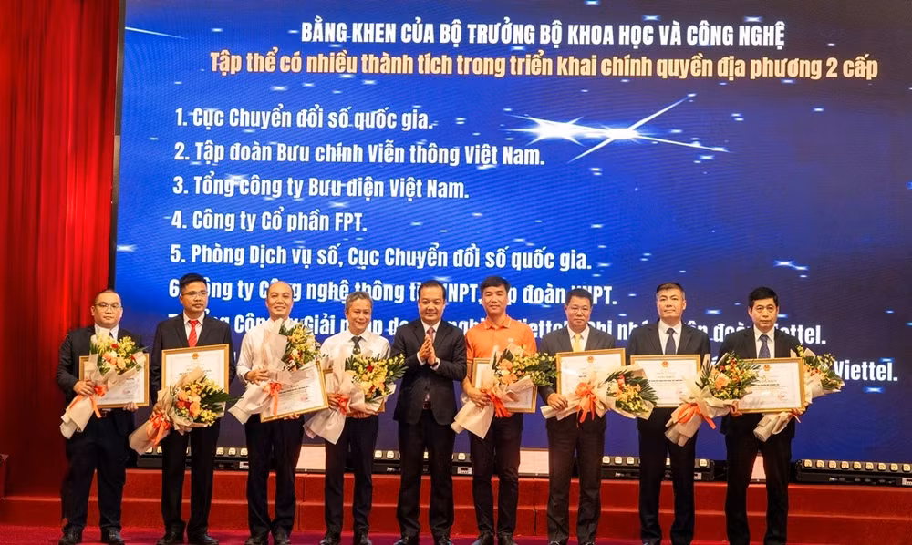 Đại diện FPT (áo cam) vinh dự nhận bằng khen của Bộ trưởng Bộ Khoa học & Công nghệ cho những đóng góp trong việc chuyển đổi các hệ thống công nghệ thông tin quan trọng đáp ứng vận hành Mô hình chính quyền 2 cấp.