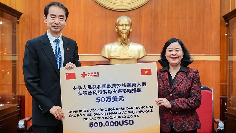 Đồng chí Bùi Thị Minh Hoài thay mặt Lãnh đạo Đảng, Nhà nước Việt Nam tiếp nhận số kinh phí hỗ trợ khắc phục hậu quả thiên tai, mưa lũ từ đồng chí Hà Vĩ, Đại sứ Trung Quốc tại Việt Nam. 