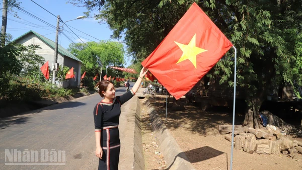 Bí thư Chi bộ buôn Tuôr, xã Hòa Phú H'Lin H'Đớt treo cờ Tổ quốc hướng về Đại hội XIV của Đảng.