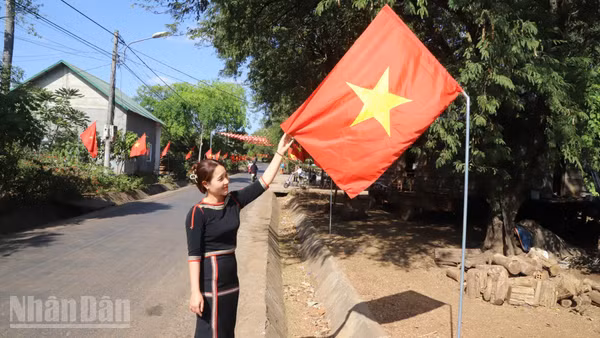 Bí thư Chi bộ buôn Tuôr, xã Hòa Phú H'Lin H'Đớt treo cờ Tổ quốc hướng về Đại hội XIV của Đảng.