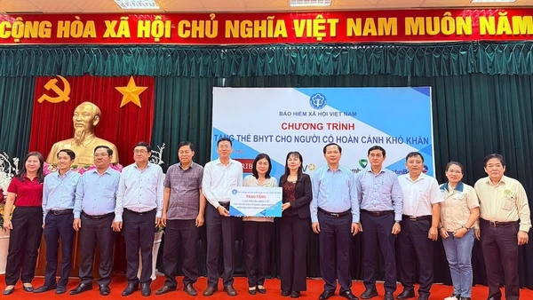 Trao biểu trưng tặng thẻ BHYT cho người dân.