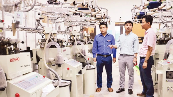 Anh Nguyễn Thanh Bình (đứng giữa), Giám đốc Công ty TNHH Begen, giới thiệu về dây chuyền sản xuất bít-tất xuất khẩu.