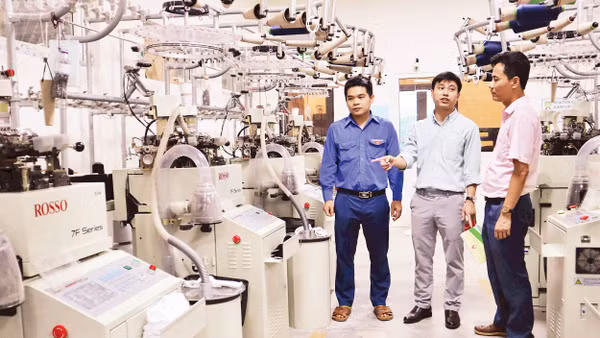 Anh Nguyễn Thanh Bình (đứng giữa), Giám đốc Công ty TNHH Begen, giới thiệu về dây chuyền sản xuất bít-tất xuất khẩu.