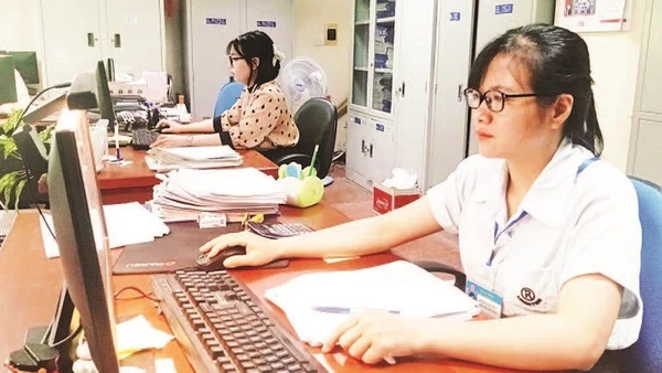 Cán bộ Đội Thuế thành phố Bắc Giang rà soát hồ sơ để thực hiện giảm tiền thuê đất cho doanh nghiệp. (Ảnh MINH LINH)