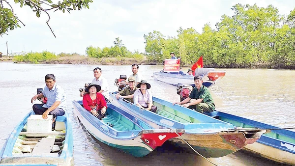 Cán bộ đến tận những căn nhà dân dựng ven sông để trao thẻ cử tri, mang lại niềm vui và sự an tâm cho người dân vùng sâu.