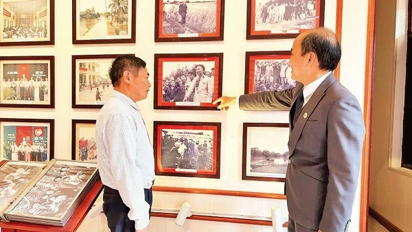 Ông Phùng Văn Tiệp (bên phải), Trưởng phòng Văn hóa-Xã hội xã Dân Hòa giới thiệu cho khách tham quan các hình ảnh về Chủ tịch Hồ Chí Minh tại Nhà lưu niệm Chủ tịch Hồ Chí Minh tại xã Dân Hòa.