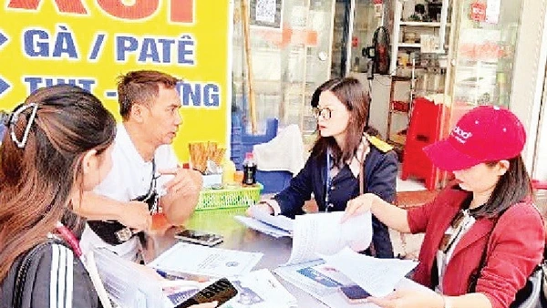 Cán bộ ngành Thuế Hà Nội phát tờ rơi và phiếu khảo sát, tuyên truyền chủ trương đến hộ kinh doanh tại phường Yên Hòa.