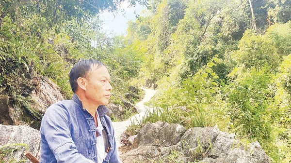 Bí thư Chi bộ Thào A Quả bên một đoạn đường anh đã vận động bà con chung sức hoàn thành. Ảnh: Doãn Hoàng 