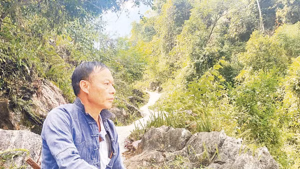 Bí thư Chi bộ Thào A Quả bên một đoạn đường anh đã vận động bà con chung sức hoàn thành. Ảnh: Doãn Hoàng 