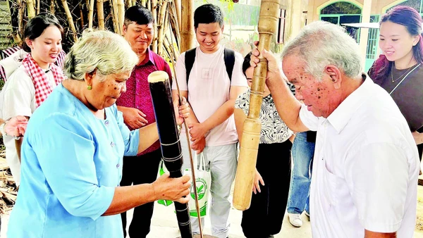 Vợ chồng ông Thạch Sang giã cốm dẹp cho khách du lịch xem.