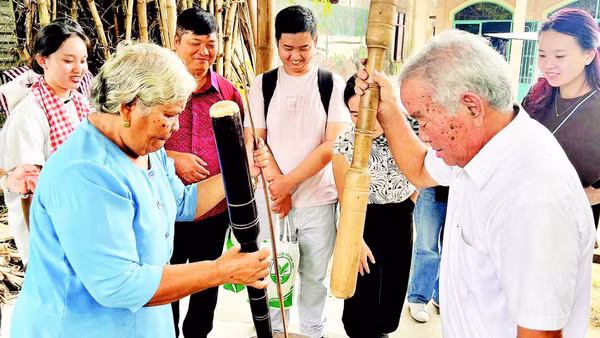 Vợ chồng ông Thạch Sang giã cốm dẹp cho khách du lịch xem.