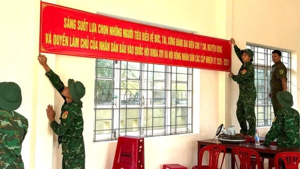 Cán bộ, chiến sĩ Đồn Biên phòng Xuân Hòa treo băng rôn tuyên truyền, hoàn thiện công tác trang trí tại khu vực bỏ phiếu trên địa bàn xã Xuân Cảnh.