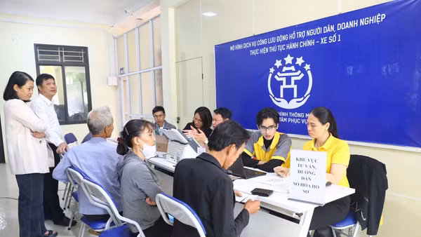 Người dân xã Minh Châu được cán bộ, tình nguyện viên tư vấn, hướng dẫn và thực hiện thủ tục hành chính tại điểm phục vụ theo mô hình “Dịch vụ công lưu động”. (Ảnh TTXVN)