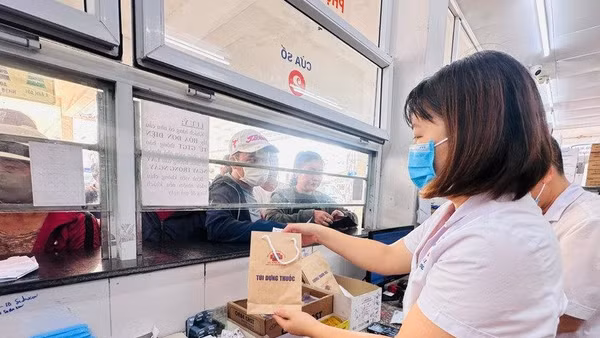 Nhân viên y tế cấp phát thuốc bảo hiểm y tế cho người bệnh. (Ảnh Thùy Giang)
