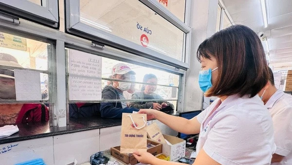 Nhân viên y tế cấp phát thuốc bảo hiểm y tế cho người bệnh. (Ảnh Thùy Giang)