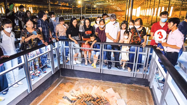 Du khách được nghe hướng dẫn viên thuyết minh về những chiếc giếng cổ trong khu nền móng kiến trúc cung điện và lầu lục giác thời Lý (thế kỷ XI - XII) tại tour trải nghiệm Hoàng thành Thăng Long về đêm. (Ảnh Thành Đạt)