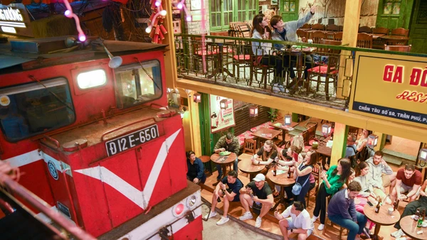 Khách du lịch ngồi sát khu vực đường ray khi tàu đi qua.