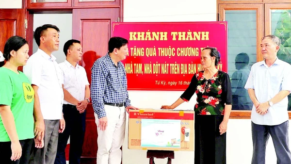 Đại diện chính quyền địa phương tặng quà gia đình bà Phạm Thị Thoa (ở xã Lạc Phượng) được hỗ trợ xây nhà mới.